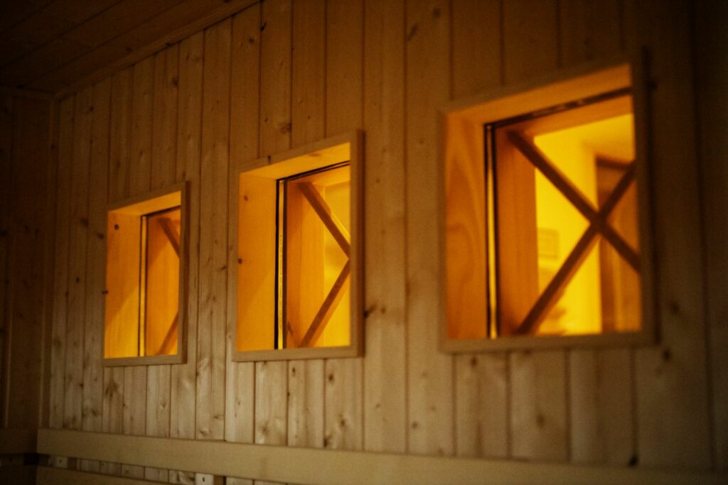 Saunenaußenwand aus Holz mit 3 viereckigen beleuteten Fenstern
