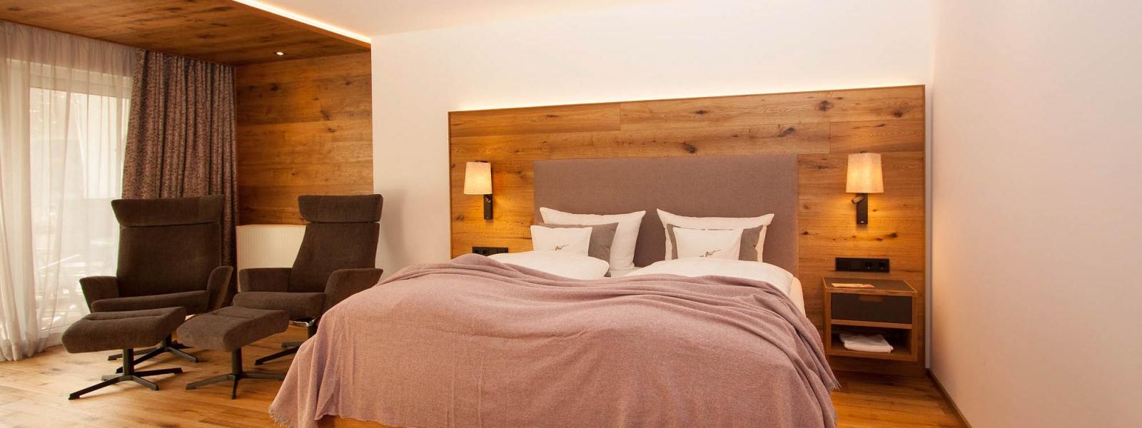 Double room at Hotel Voss with bed and two comfortable armchairs with footstool