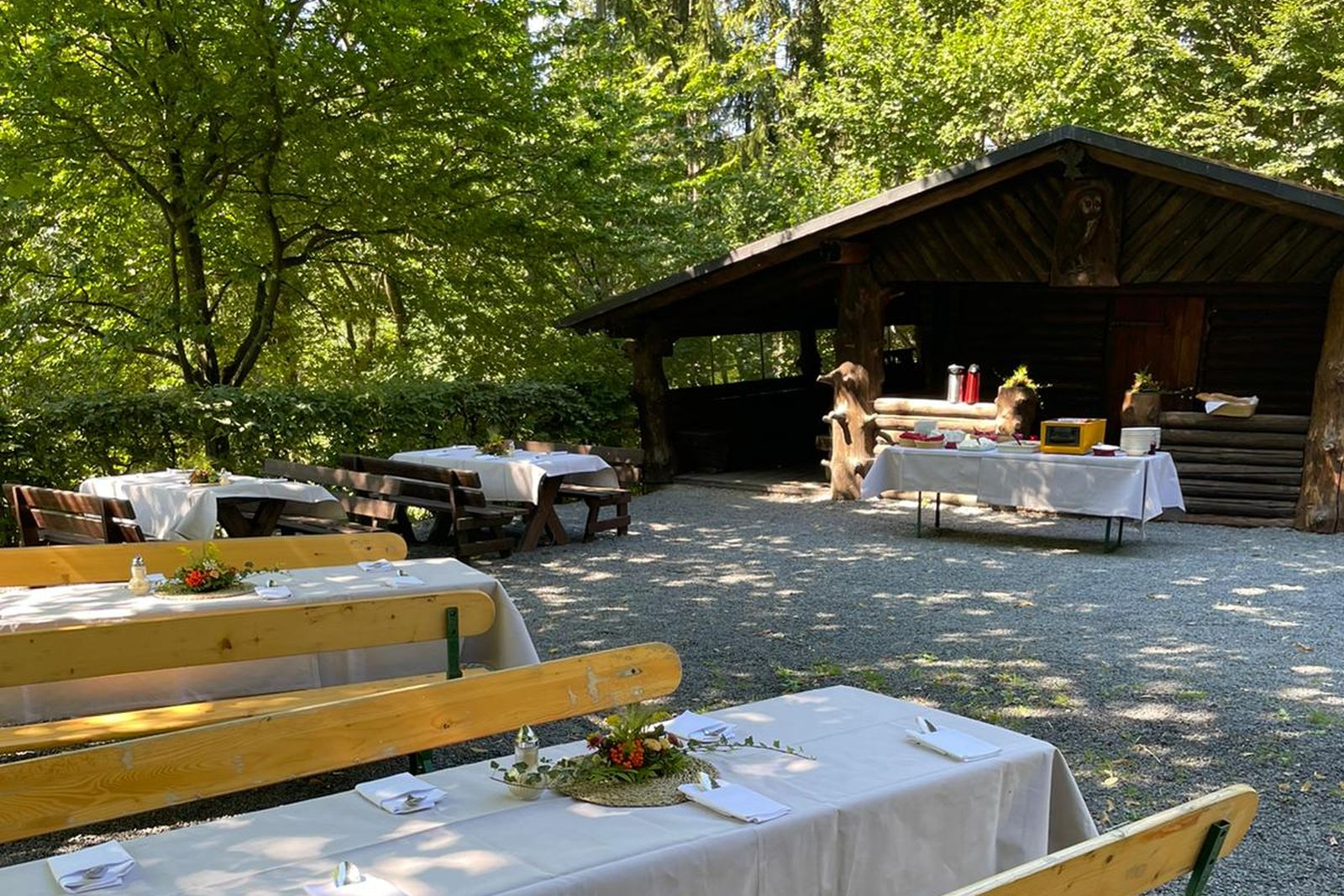 Schutzhütte im Wald mit Vierbänken und Essensbuffet