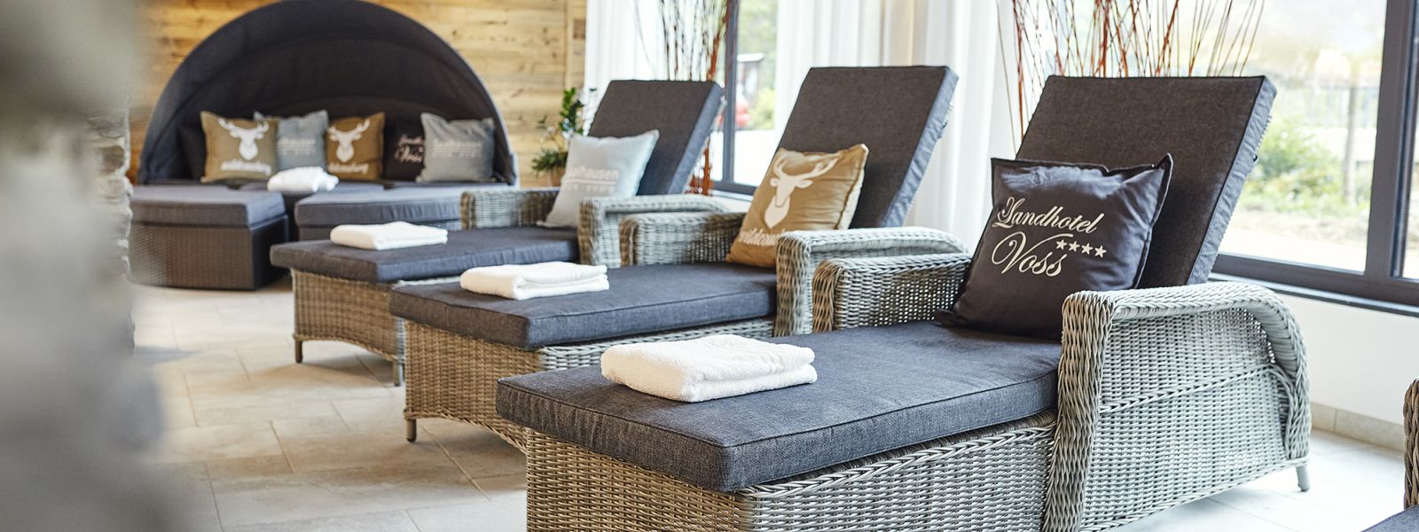 Relaxation area with comfortable loungers in the Hotel Voss; the loungers are equipped with thick cushions, a pillow and a towel each