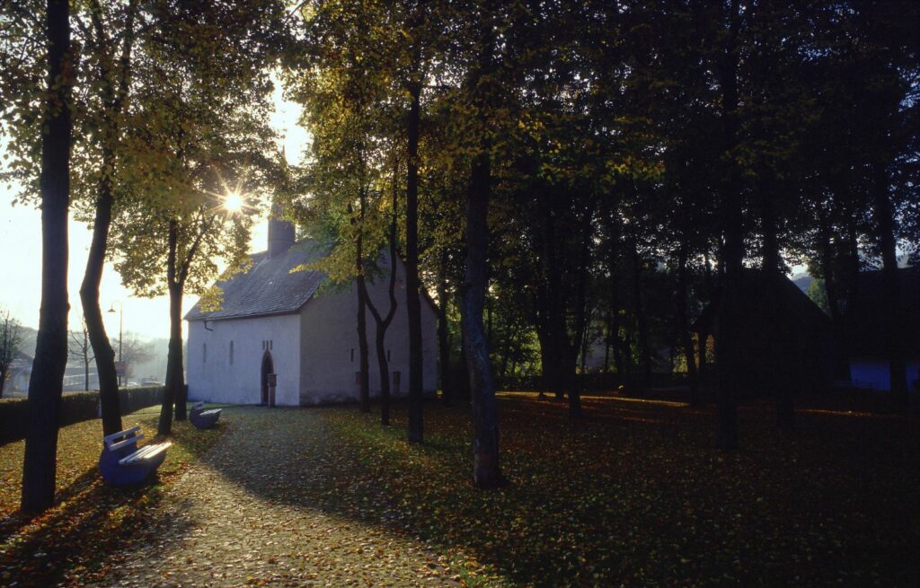 Blick auf die Wallfahrtskirche Hallenberg, die Sonne scheint durch die Bäume