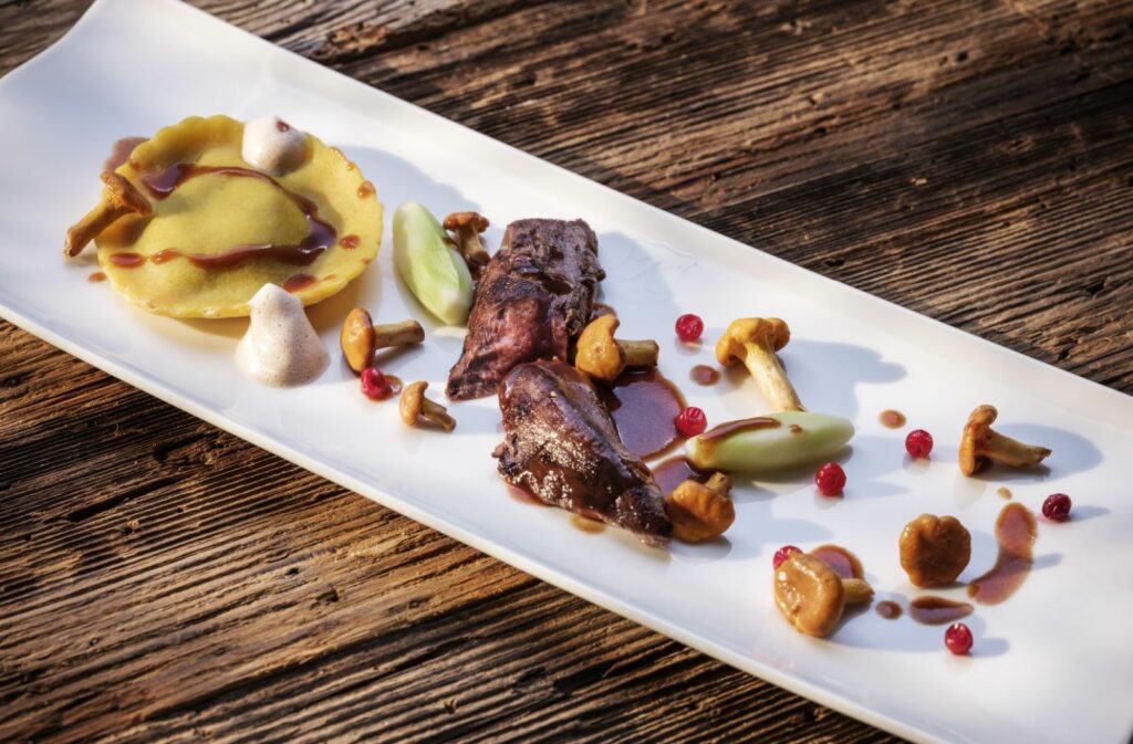 Fleisch mittig auf länglichem Teller angerichtet mit Pfifferlingen, Tortellini und Sauce