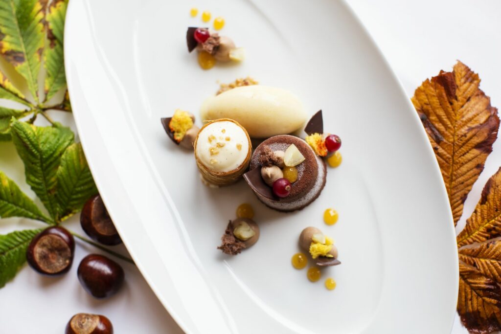Dessertsteller mit Schokoküchlein und weißem Schokomousse, dekoriert mit herbstlichem Laub und Kastanien