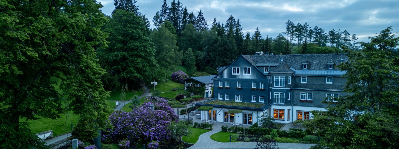 Exterior view of the hunting lodge meadow in spring with flowering rhododendron bushes