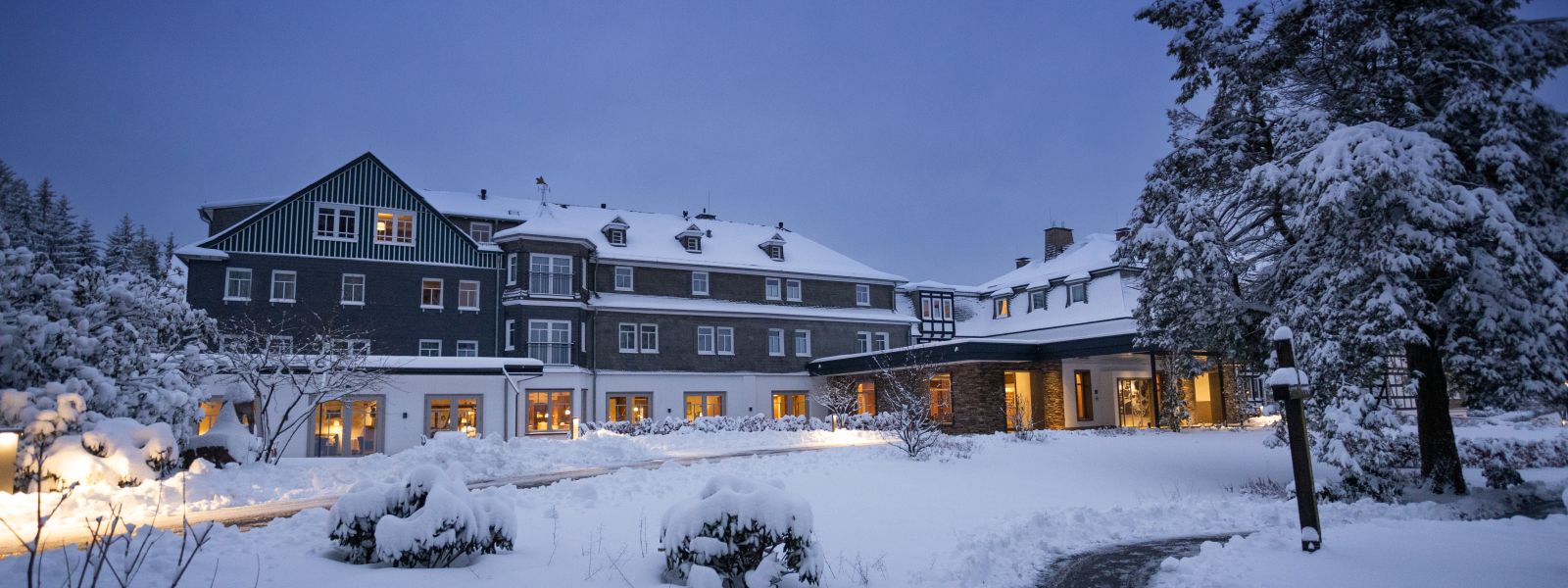 Hunting lodge Wiese, covered in deep snow in the twilight, windows are illuminated