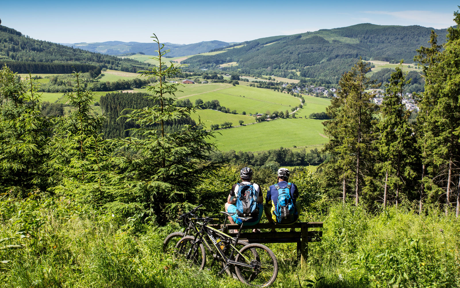 Ideale Aussichten für Radtouren im Sauerland Zwei Radfahrer auf einer Bank mit Aussicht ins Tal