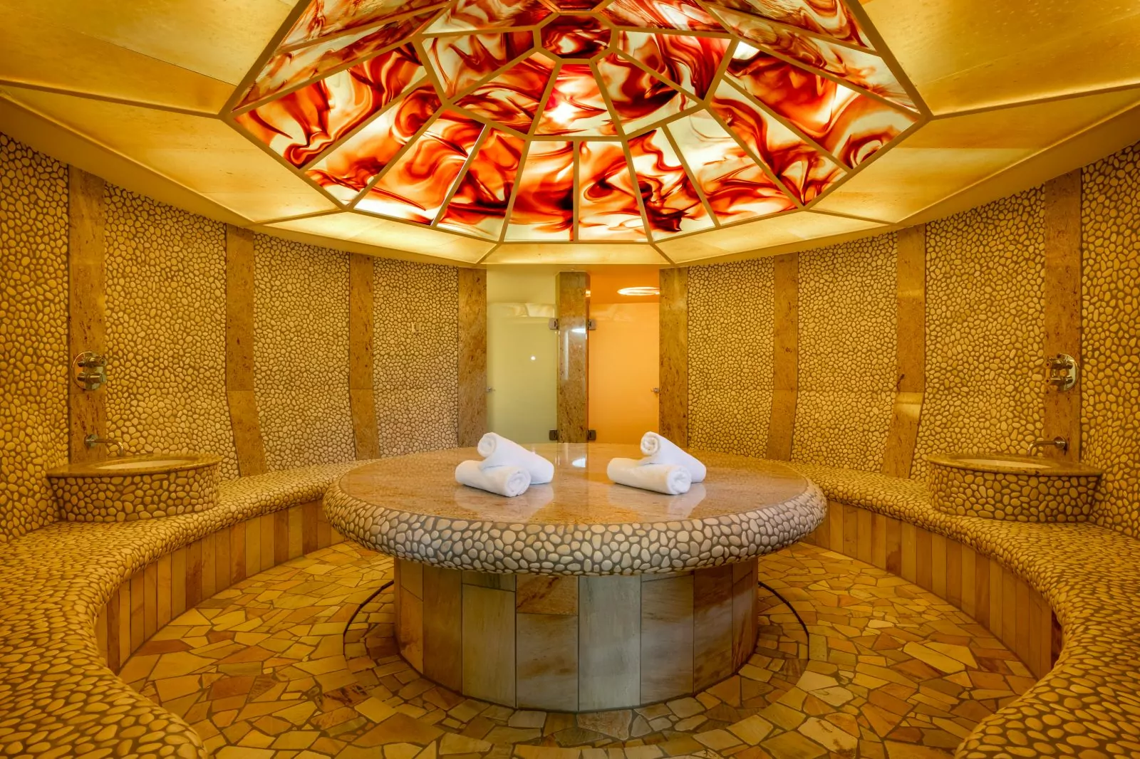 Hotel Deimann – Hamam Hamam mit bunter Glasdecke und massivem Marmortisch, auf dem Tisch liegen Handtücher
