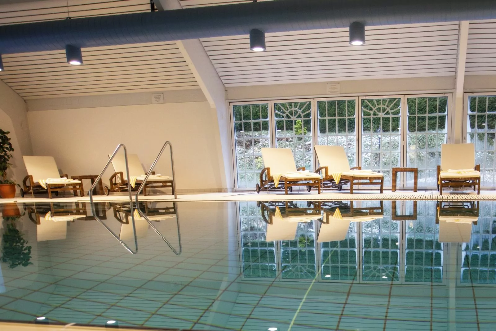 Hotel Platte – Schwimmbad Blick über das Wasser im Pool auf 5 Liegestühle am Beckenrand