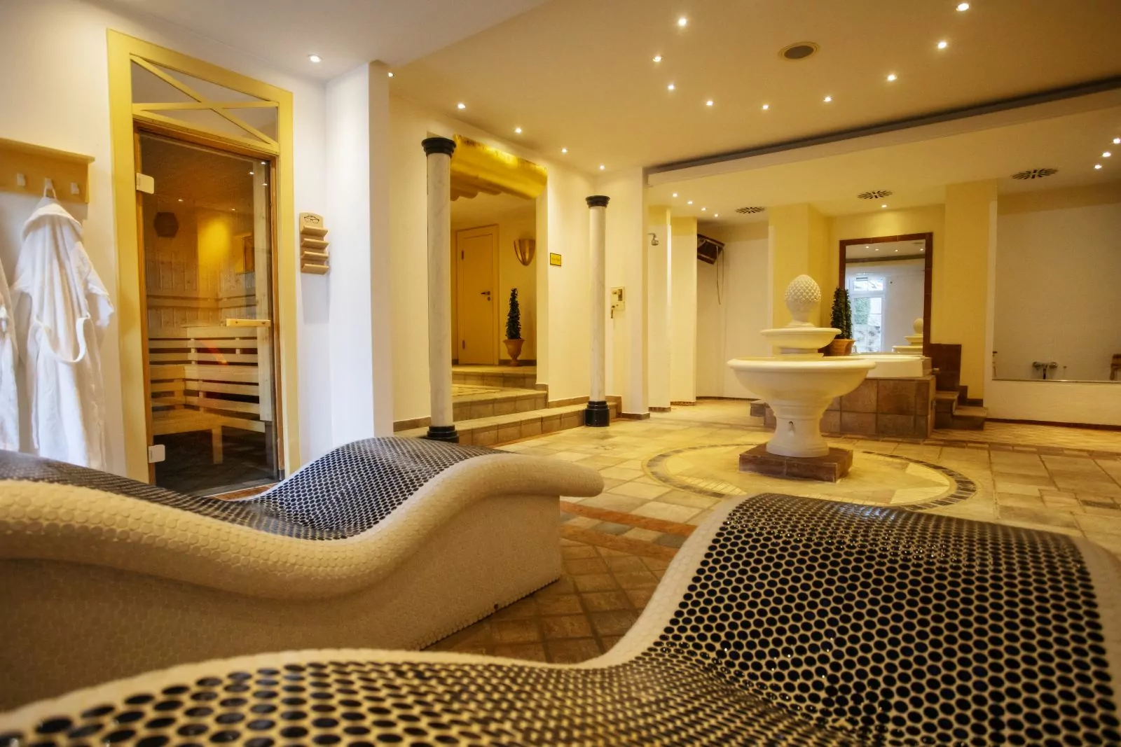 Hotel Platte – Wellness & Sauna Bereich Vorraum des Saunabereichs mit links Eingang zur Sauna und rechts dem Wasserfußbecken. Im Vordergrund zwei Steinliegen