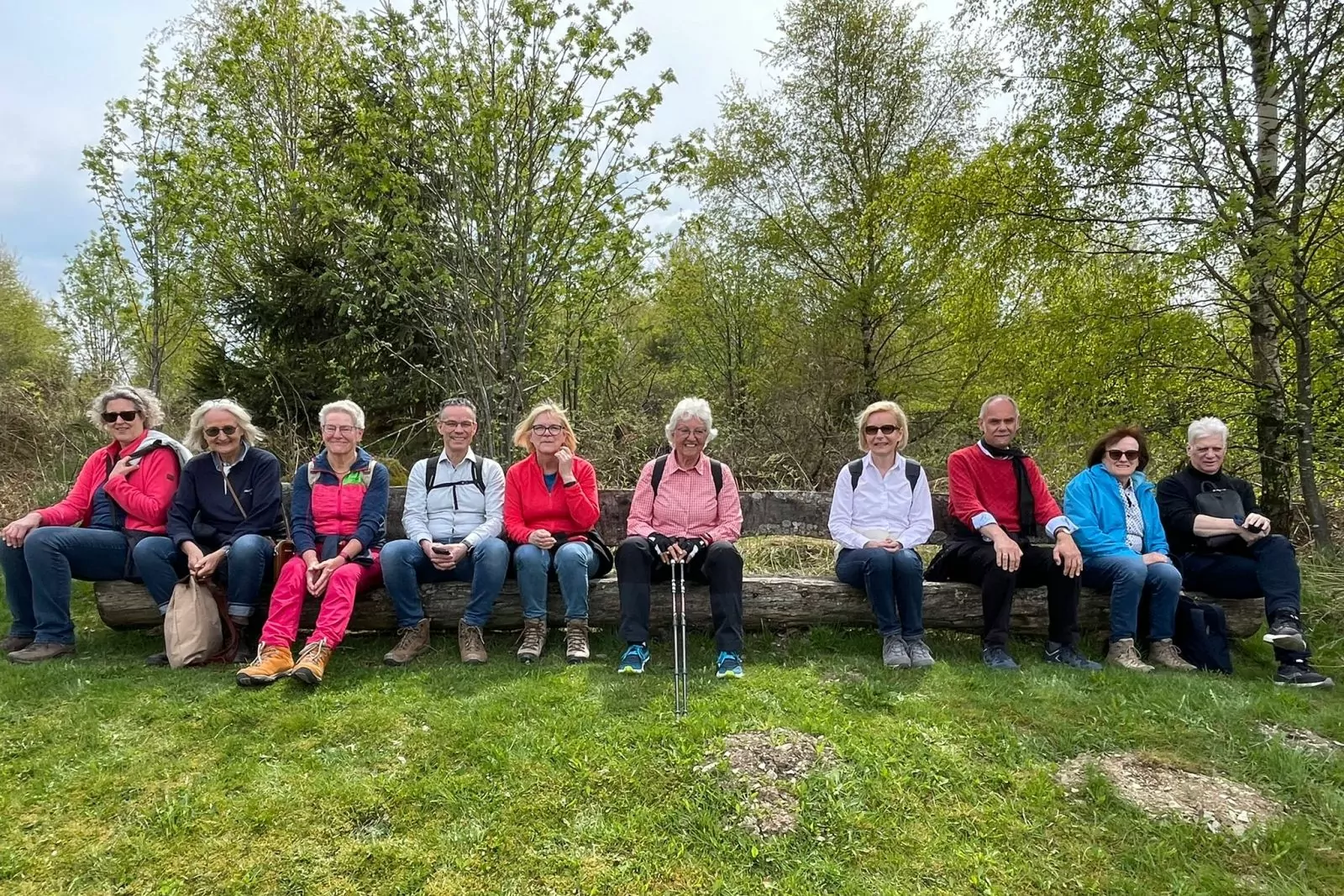 Wanderergruppe macht Pause auf einem Baumstamm