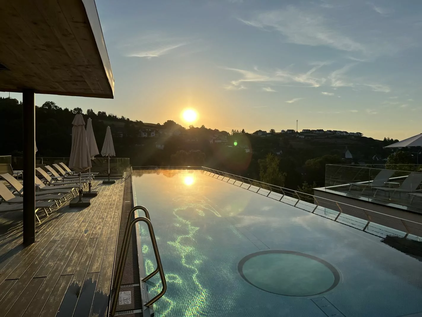 Diedrich – Infinity Pool 2 Außenpool bei strahlendem Sonnenaufgang, die Sonne spiegelt sich im Poolwasser