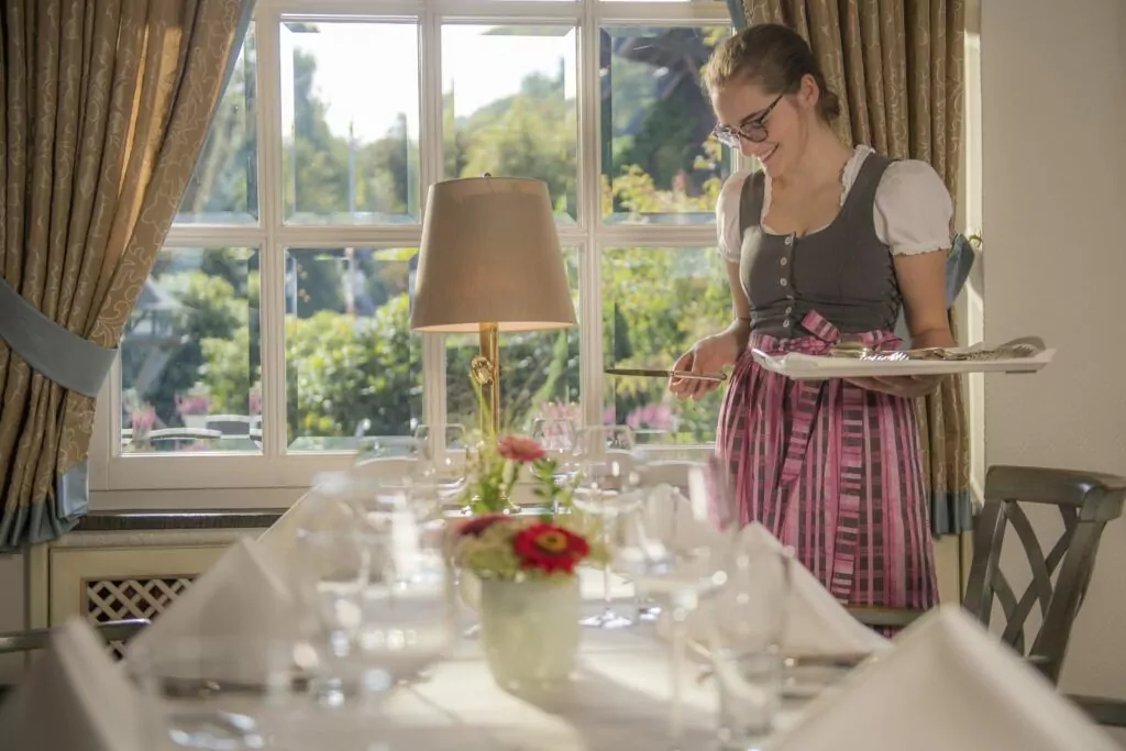 Mitarbeiterin deckt Besteck am Tisch ein