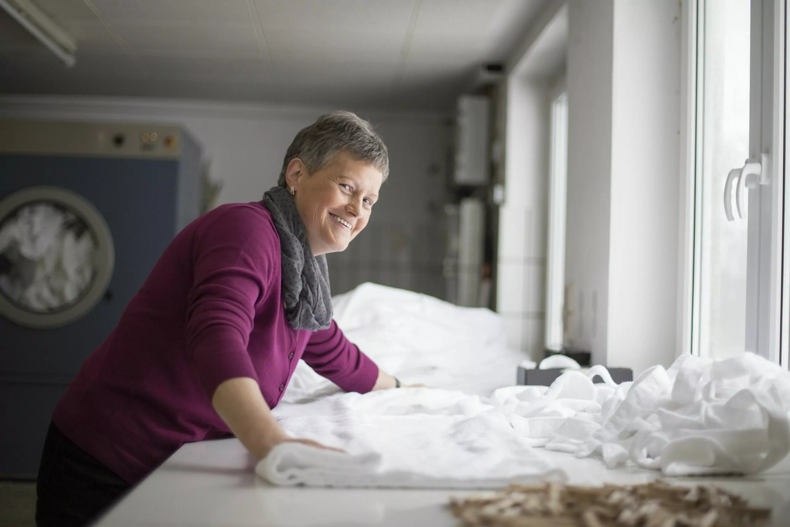 Mitarbeiterin im Housekeeping faltet Bademäntel in der Waschküche