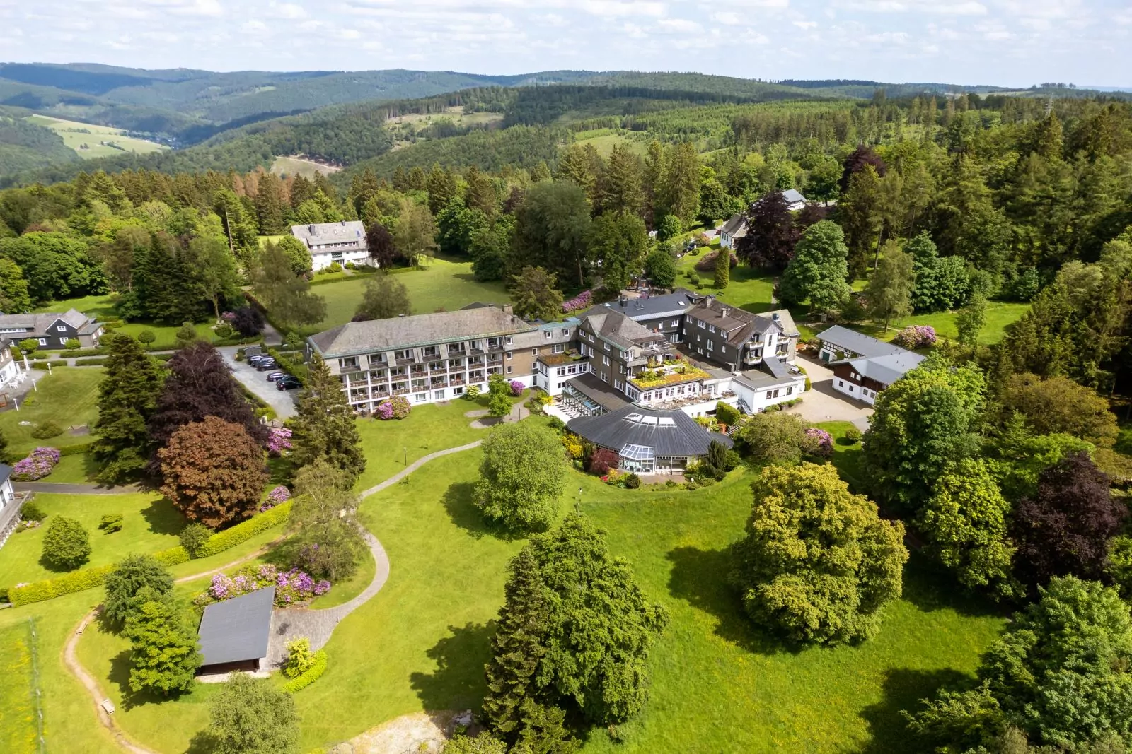 Jagdhaus Wiese Luftaufnahme Luftaufnahme vom Hotel im Frühling mit Farbtupfern von blühenden Rhododendronbüschen