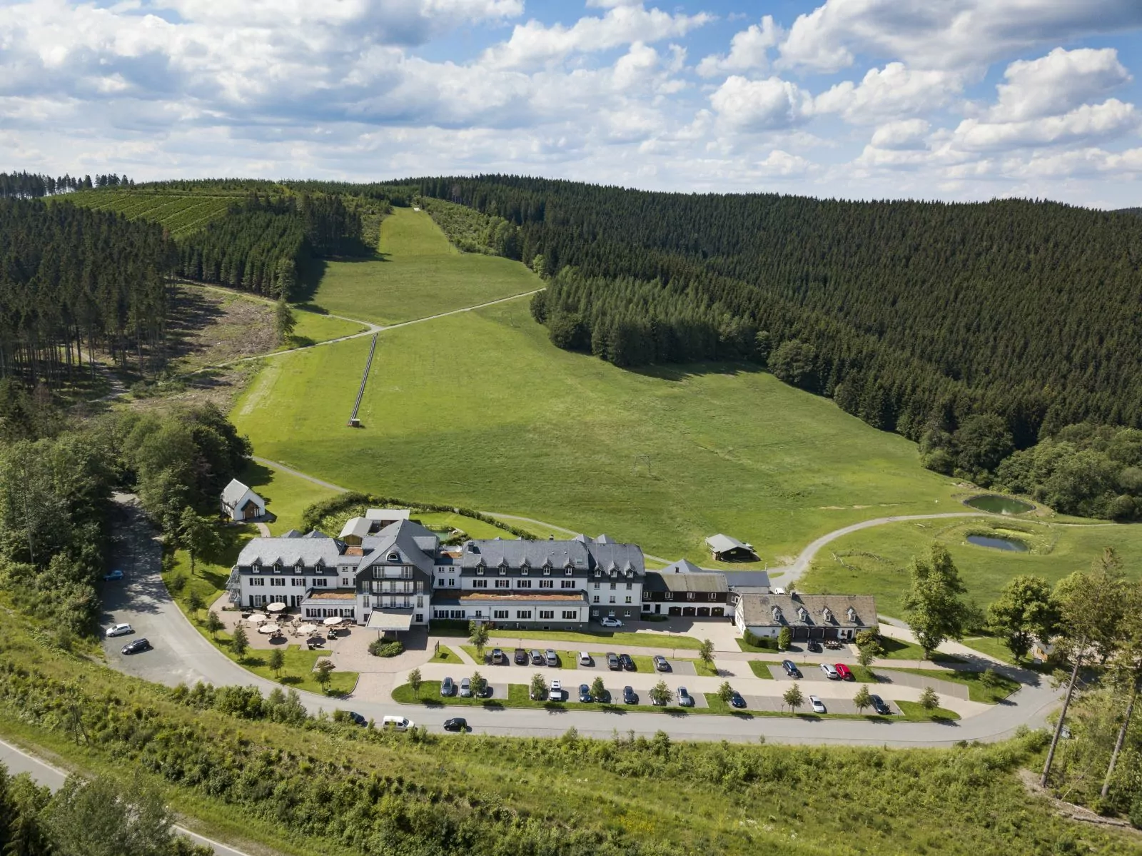 Luftaufnahme des Hotels und des grünen Rimbergs im Sommer