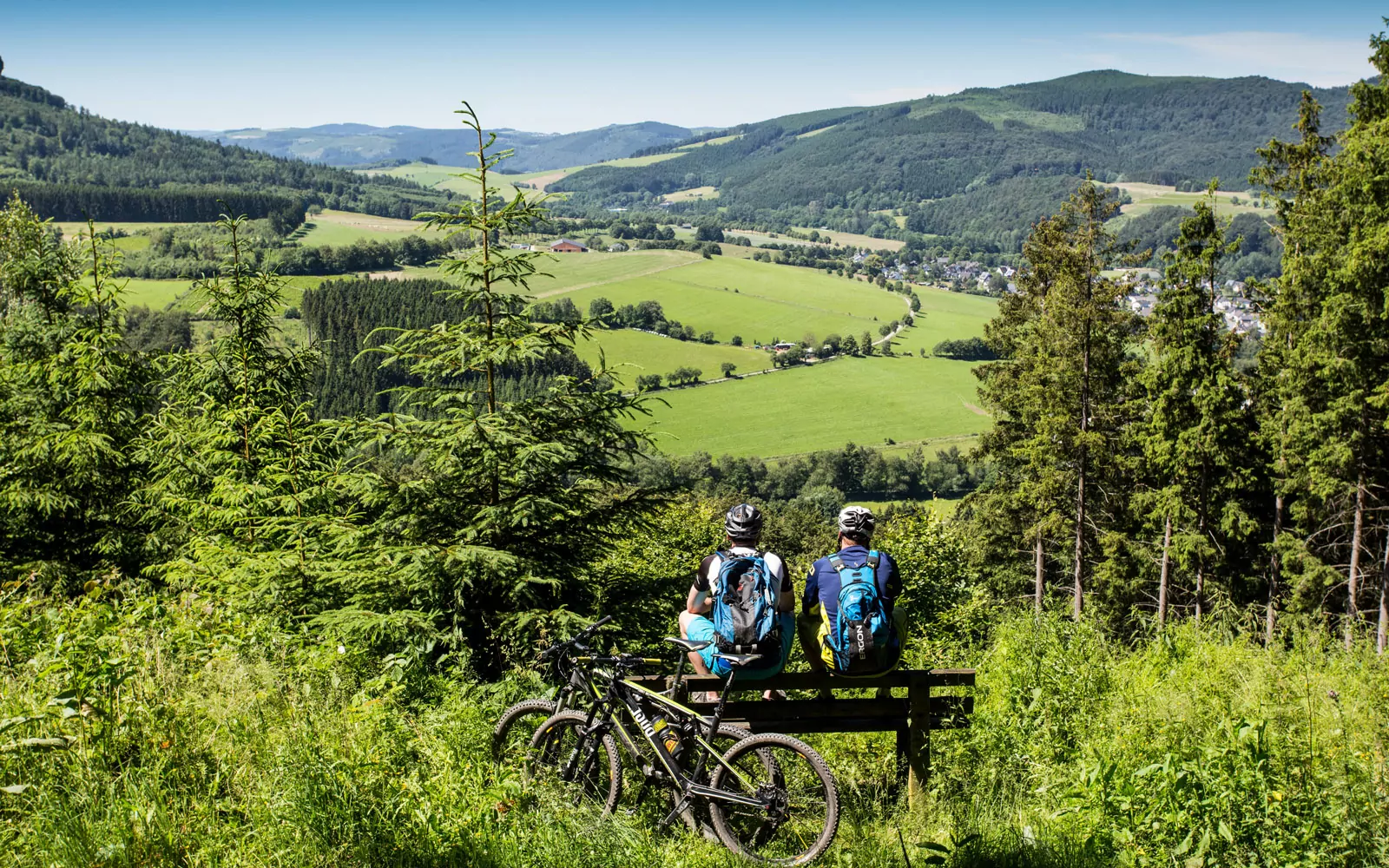 Two cyclists on a bench with a view of the valley